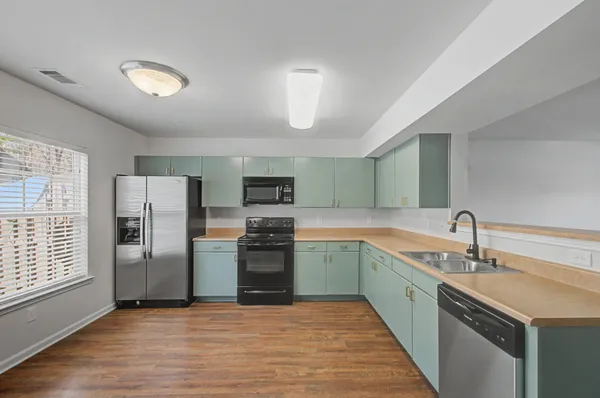 a kitchen with stainless steel appliances granite countertop a kitchen island hardwood floor and a sink
