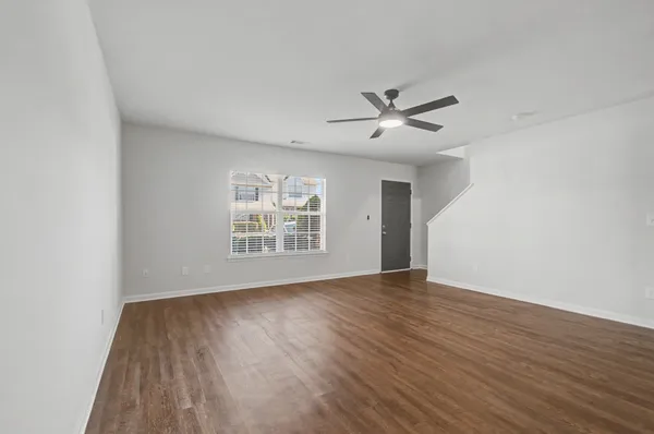 a view of a room with wooden floor and a ceiling fan
