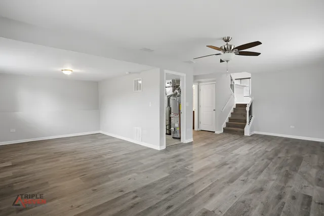 a view of empty room with wooden floor and ceiling fan