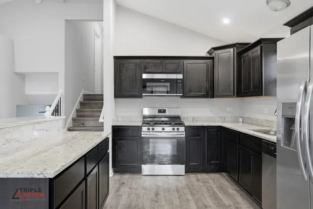 a kitchen with stainless steel appliances granite countertop a stove a sink and a microwave