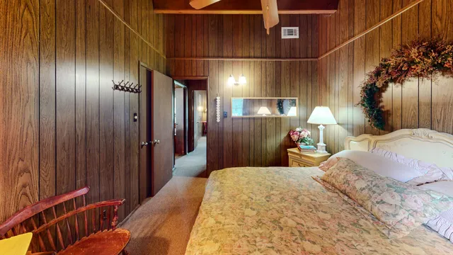 a spacious bedroom with a bed table and a chair