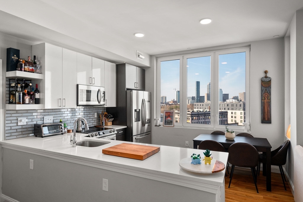 10 Taber Street, Unit 608 Boston, MA 02119 - Photo 18 of 20 a kitchen with stainless steel appliances wooden floor and a refrigerator