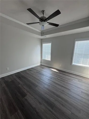 an empty room with wooden floor fan and windows