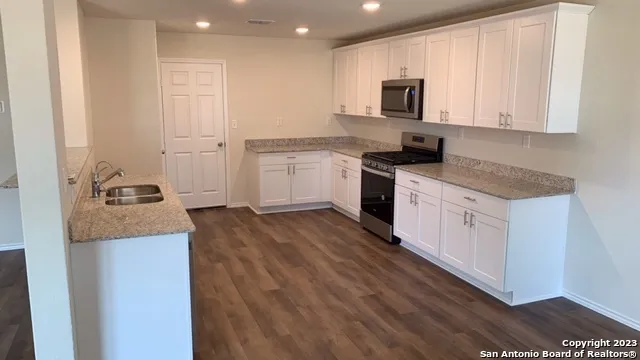 a kitchen with granite countertop white cabinets and stainless steel appliances