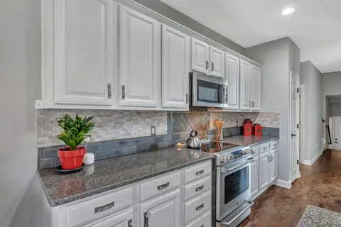 a kitchen with granite countertop white cabinets stainless steel appliances and sink