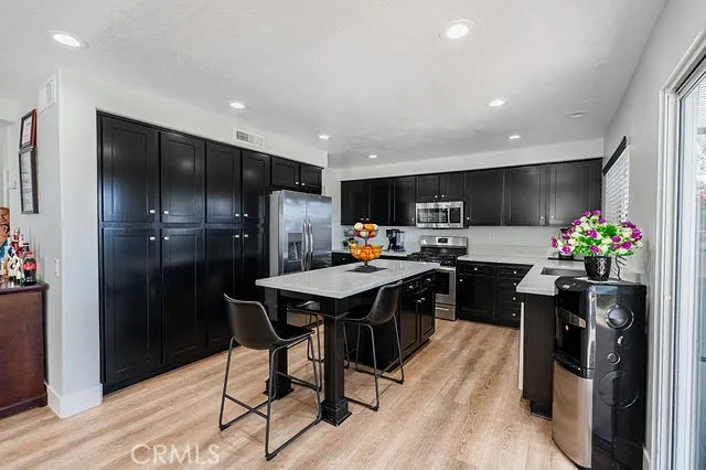 a kitchen with stainless steel appliances kitchen island granite countertop a refrigerator a stove a microwave oven a sink with island and chairs