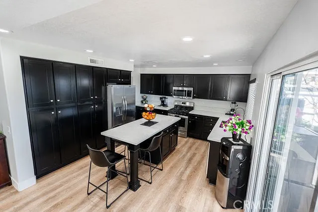 a kitchen with a refrigerator a stove a sink dishwasher a dining table and chairs with wooden floor