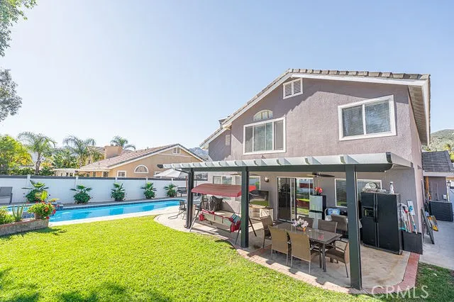 a view of a house with a yard and table and chairs under an umbrella
