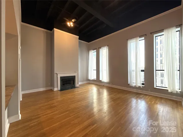 a view of an empty room with wooden floor a fireplace