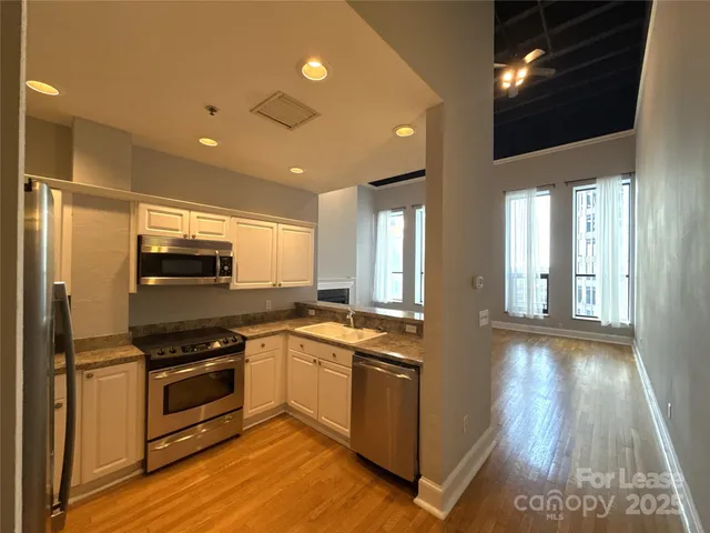 an empty room with chandelier fan and windows