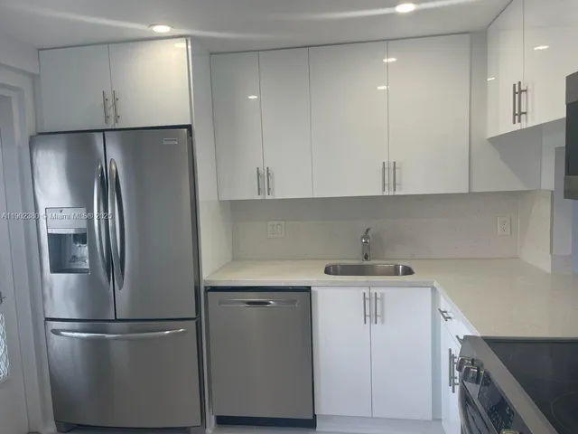 a kitchen with a refrigerator sink and cabinets