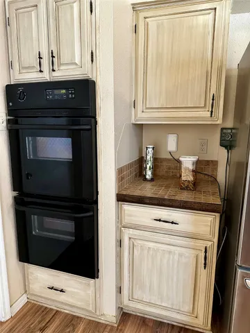 a room with stainless steel appliances wooden floor and view of kitchen