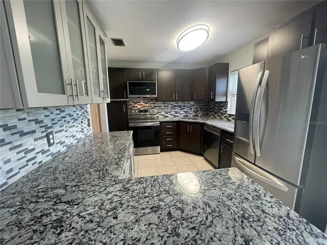a kitchen with stainless steel appliances kitchen island granite countertop a refrigerator and a stove top oven
