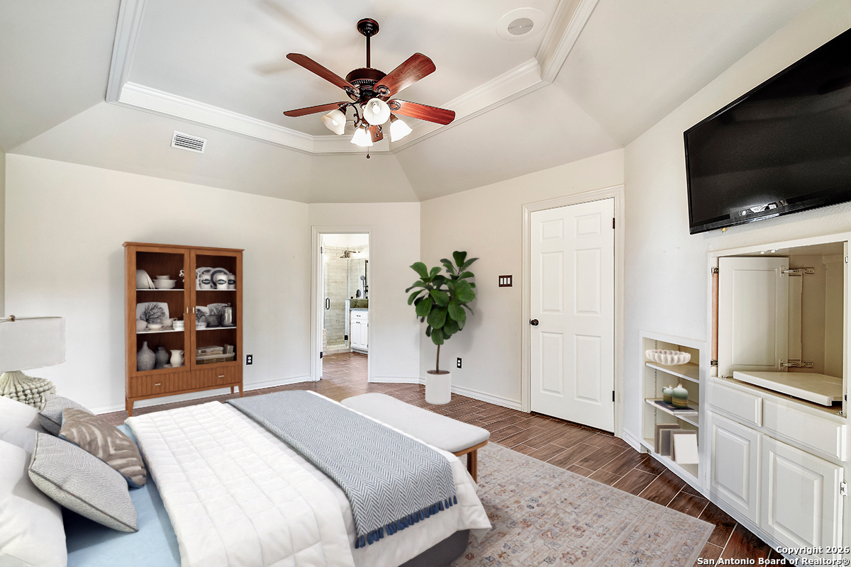 2642 Rim Oak San Antonio, TX 78232 - Photo 11 of 24 a bedroom with a large bed a flat tv screen and a chandelier