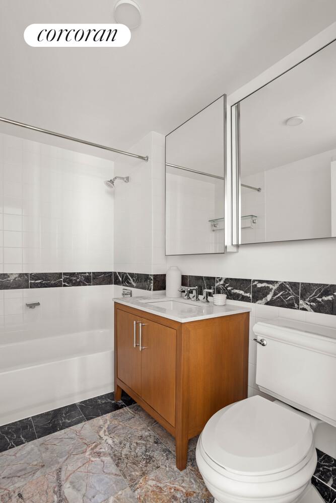 425 Main Street, Unit 14C Manhattan, NY 10044 - Photo 4 of 23 a bathroom with a sink a toilet a mirror and bathtub