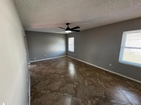 an empty room with windows and ceiling fan
