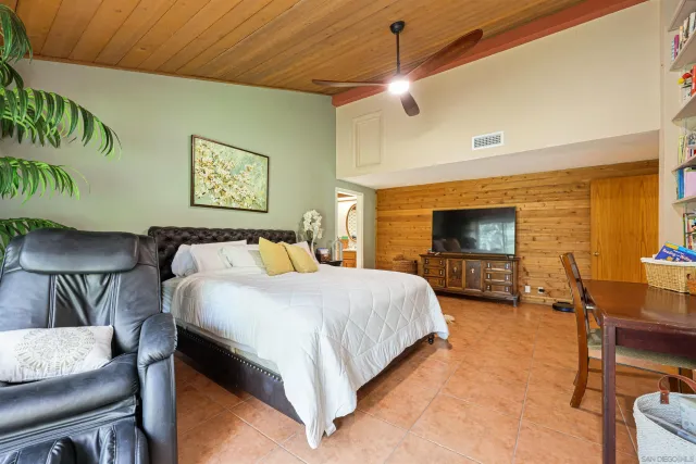 a spacious bedroom with a bed a couch and a flat screen tv