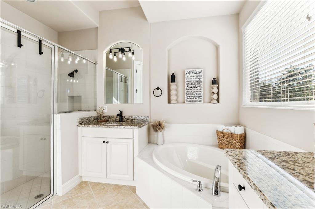 7821 Ashton Road Naples, FL 34113 - Photo 20 of 49 a spacious bathroom with a double vanity sink a mirror and a bathtub