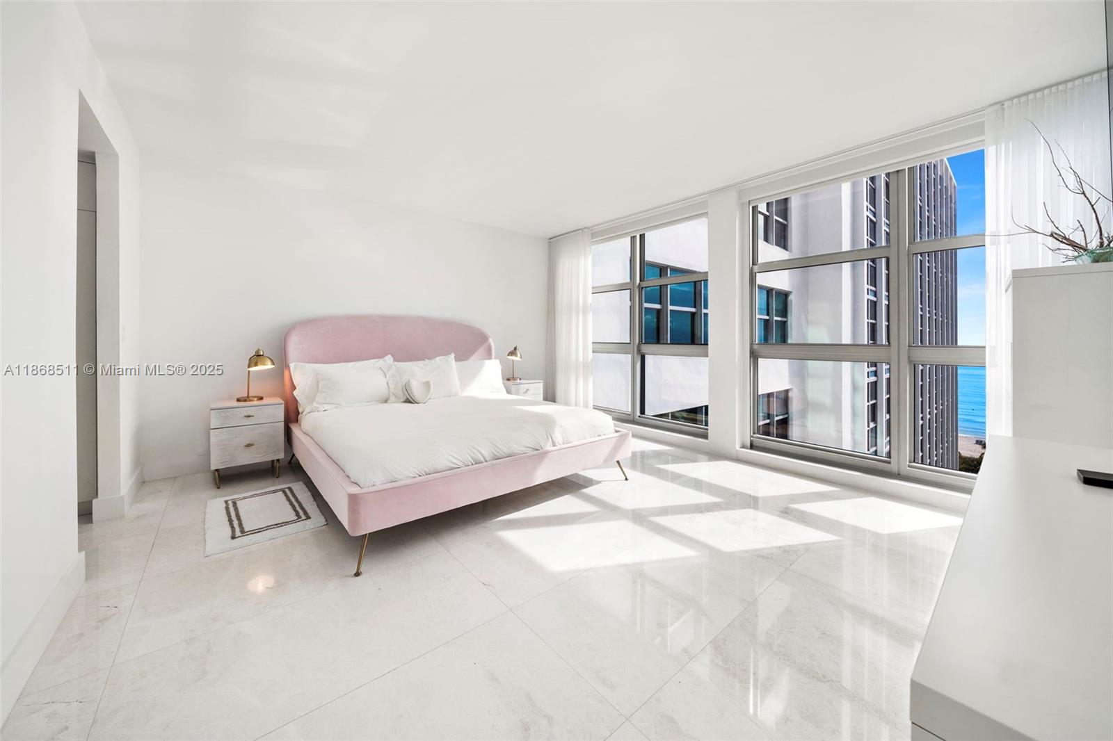 5055 Collins Avenue, Unit 10G Miami Beach, FL 33140 - Photo 11 of 20 a bedroom with a bed painting and a large window