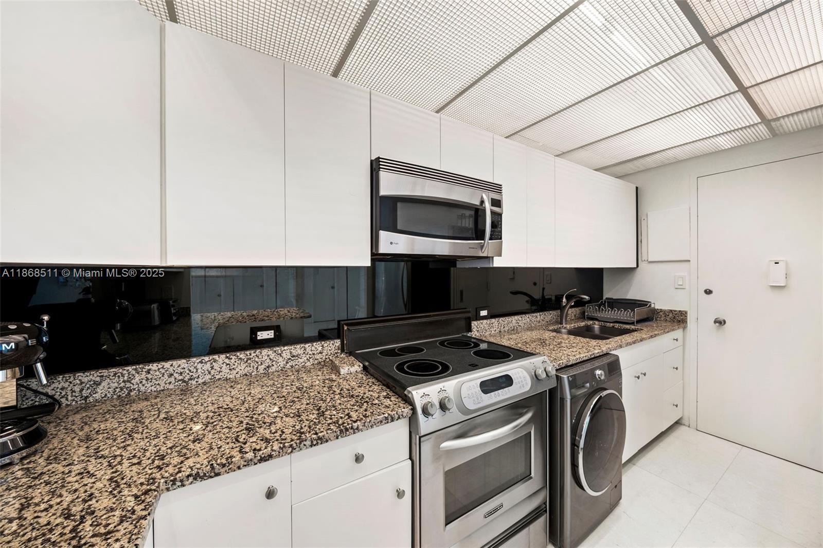5055 Collins Avenue, Unit 10G Miami Beach, FL 33140 - Photo 2 of 20 a kitchen with a stove and a microwave