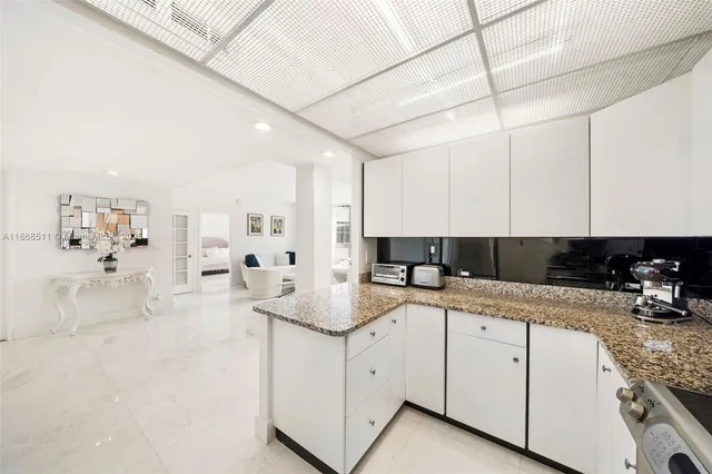 a kitchen with a sink dishwasher and white cabinets with wooden floor