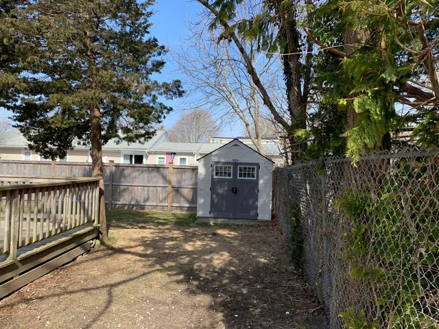 a view of a small yard in front of a house with large trees