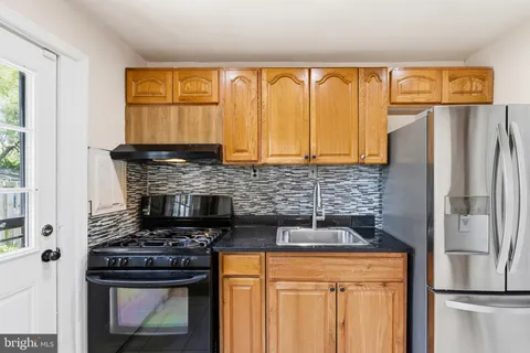 a kitchen with granite countertop a refrigerator and a stove top oven