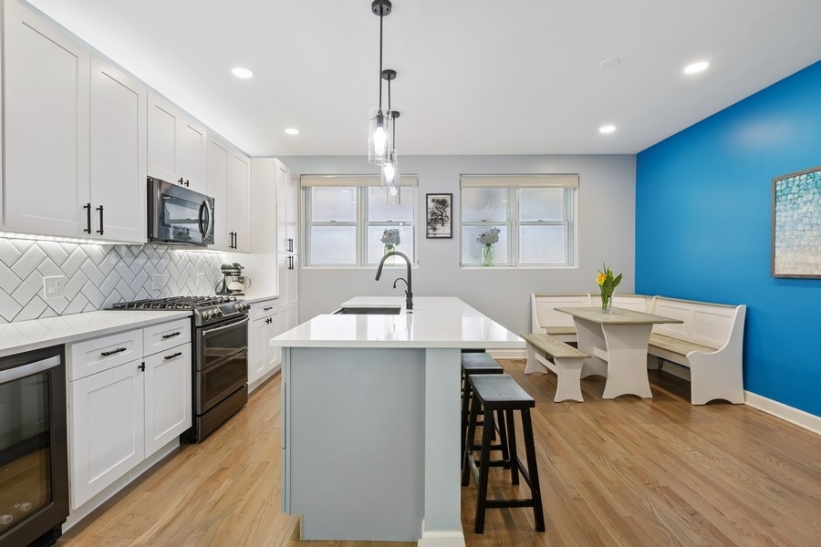 26 East 14th Place, Unit 15W Chicago, IL 60605 - Photo 11 of 36 a kitchen with stainless steel appliances kitchen island granite countertop a stove a sink a refrigerator and white cabinets with wooden floor