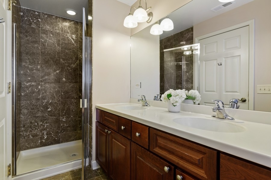 26 East 14th Place, Unit 15W Chicago, IL 60605 - Photo 29 of 36 a bathroom with a double vanity sink a large mirror and shower