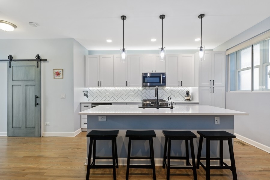 26 East 14th Place, Unit 15W Chicago, IL 60605 - Photo 8 of 36 a kitchen with stainless steel appliances kitchen island granite countertop a dining table chairs and white cabinets