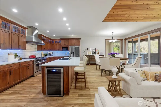 a living room with stainless steel appliances kitchen island granite countertop a table chairs sink and cabinets