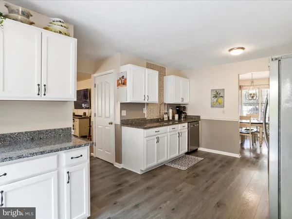 a kitchen with granite countertop white cabinets and white appliances