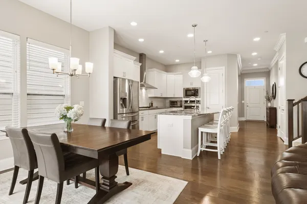 a kitchen with a dining table chairs and refrigerator