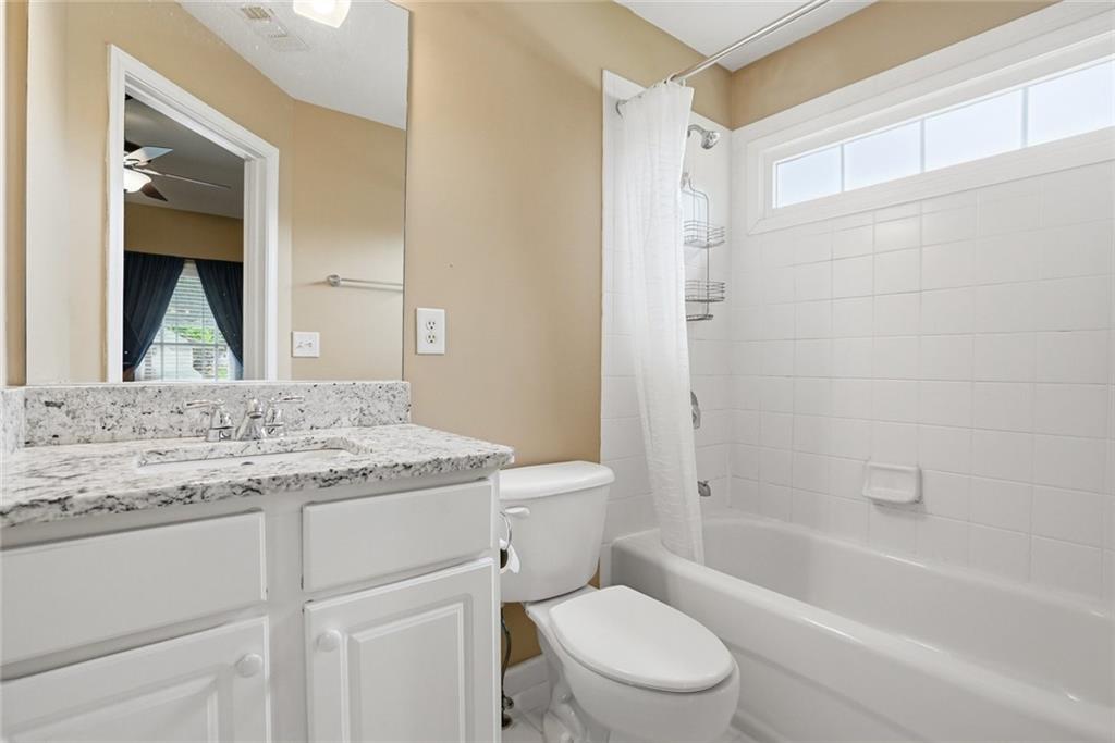 855 Freedom Way Cumming, GA 30040 - Photo 18 of 25 a bathroom with a granite countertop toilet a sink and a bathtub