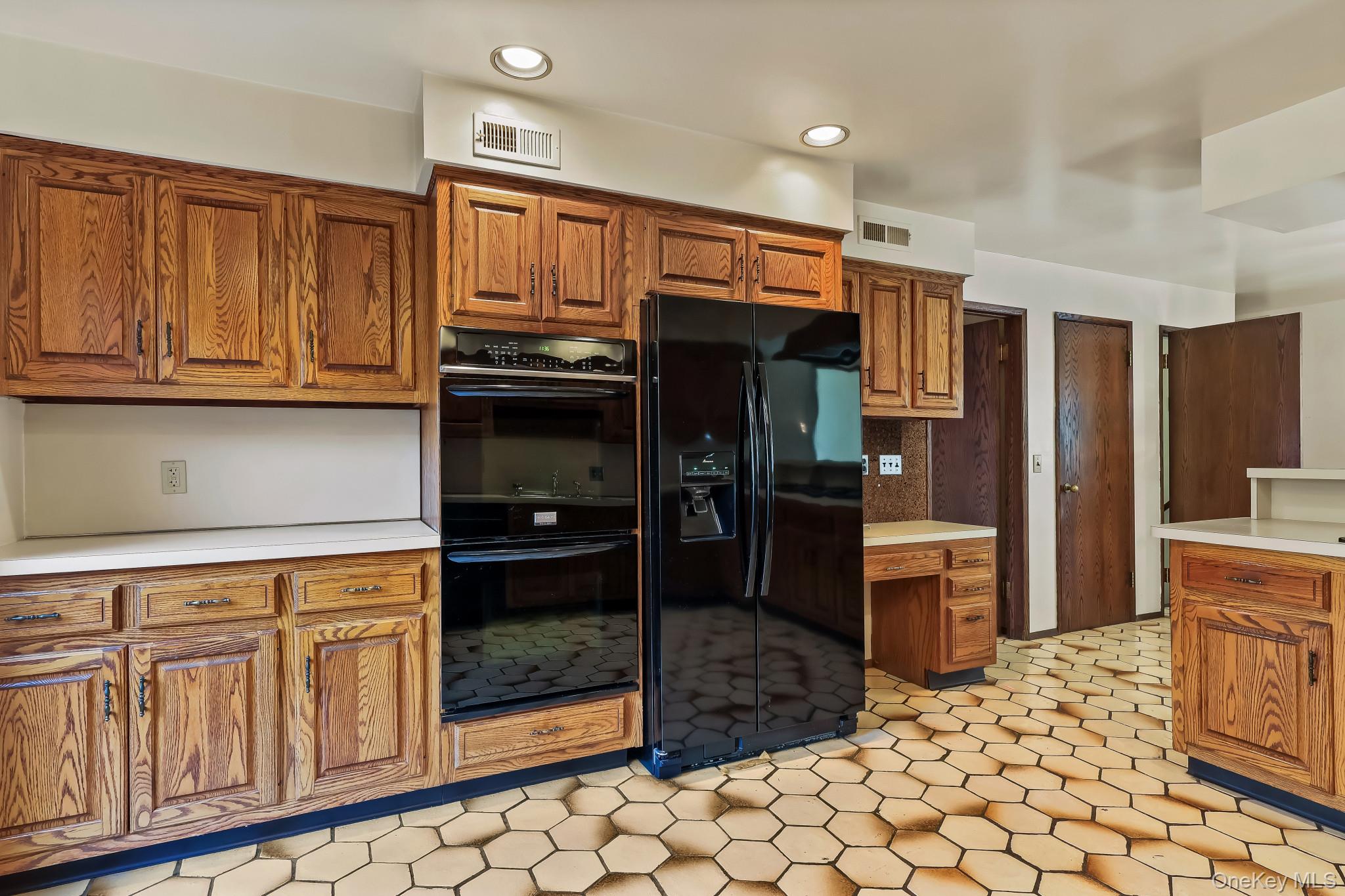 37 Century Trail Harrison, NY 10528 - Photo 13 of 43 Kitchen with brown cabinets, light countertops, black appliances, recessed lighting, and light floors