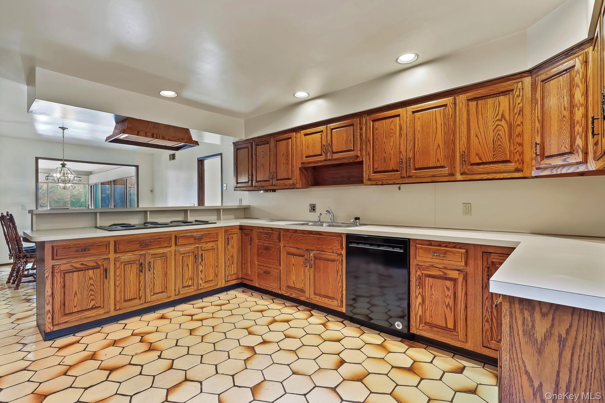 37 Century Trail Harrison, NY 10528 - Photo 15 of 43 Kitchen featuring light countertops, brown cabinetry, black appliances, a peninsula, and recessed lighting