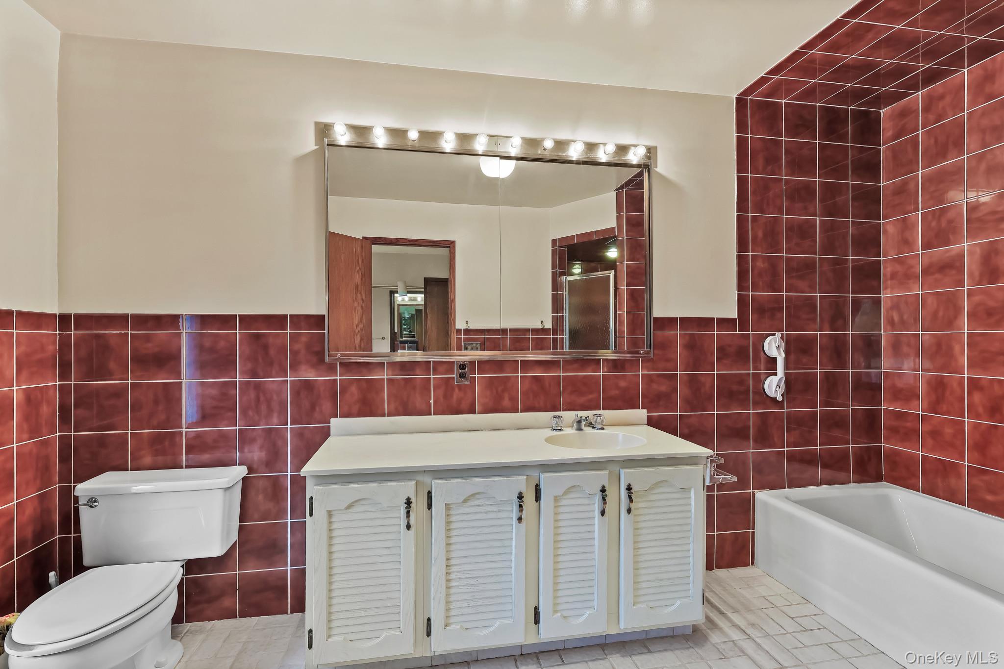 37 Century Trail Harrison, NY 10528 - Photo 21 of 43 Bathroom with tile walls, vanity, a bathtub, a wainscoted wall, and light tile patterned floors