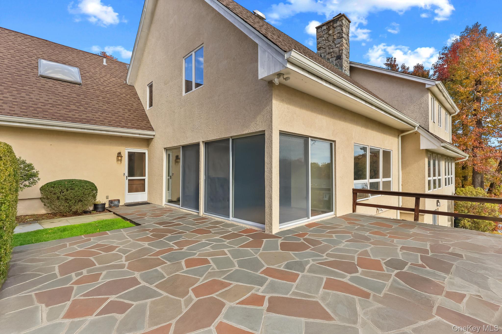 37 Century Trail Harrison, NY 10528 - Photo 39 of 43 Rear view of house featuring stucco siding, a chimney, and a terrace area