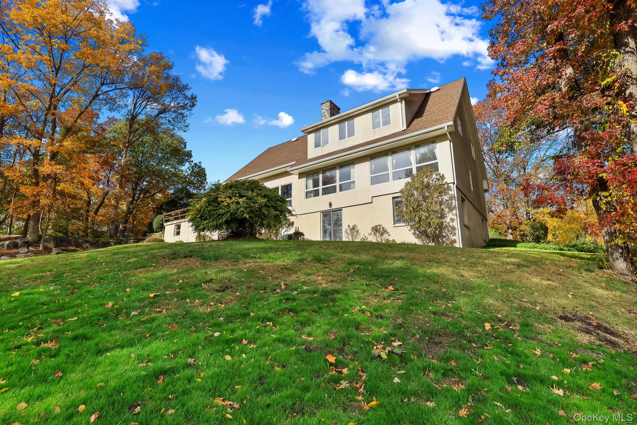 37 Century Trail Harrison, NY 10528 - Photo 41 of 43 Rear view of house with a chimney, a lawn, and stucco siding