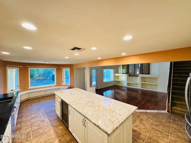 a large kitchen with kitchen island a sink stainless steel appliances wooden floor and a counter top space