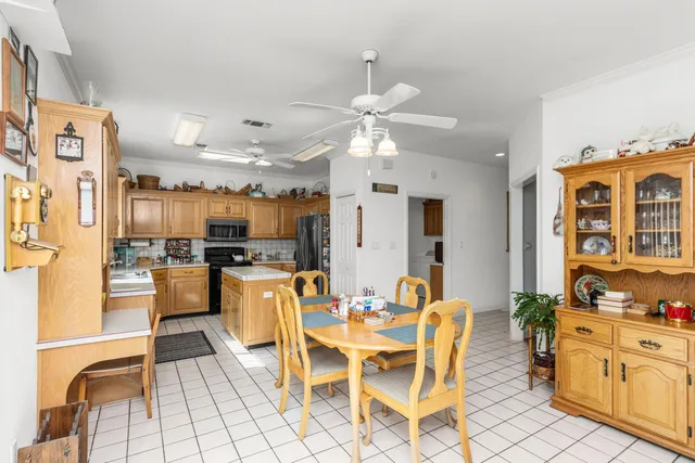 a dining hall with stainless steel appliances kitchen island granite countertop a dining table chairs and a refrigerator