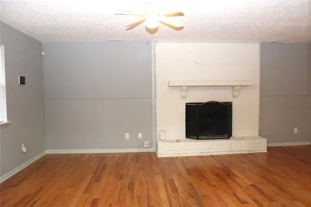 a view of empty room with wooden floor and fireplace