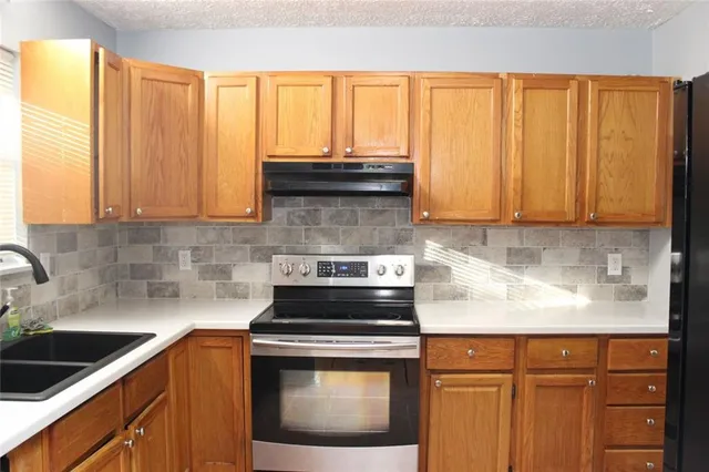 a kitchen with granite countertop a sink a stove and cabinets