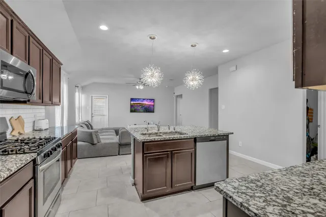 a kitchen with kitchen island granite countertop a sink stove and refrigerator