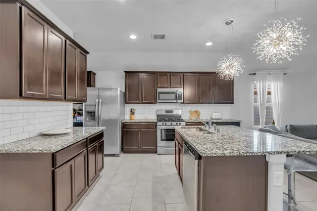 a kitchen with kitchen island granite countertop stainless steel appliances a sink stove microwave and cabinets