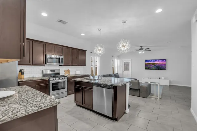 a kitchen with kitchen island granite countertop wooden cabinets and stainless steel appliances