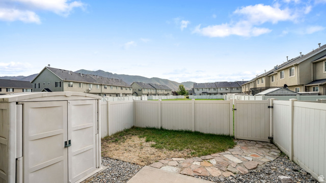 983 South 1850th Street West Springville, UT 84663 - Photo 20 of 30 Enclosed backyard featuring a light-colored privacy fence with gate access, a flagstone path, and a beige storage shed