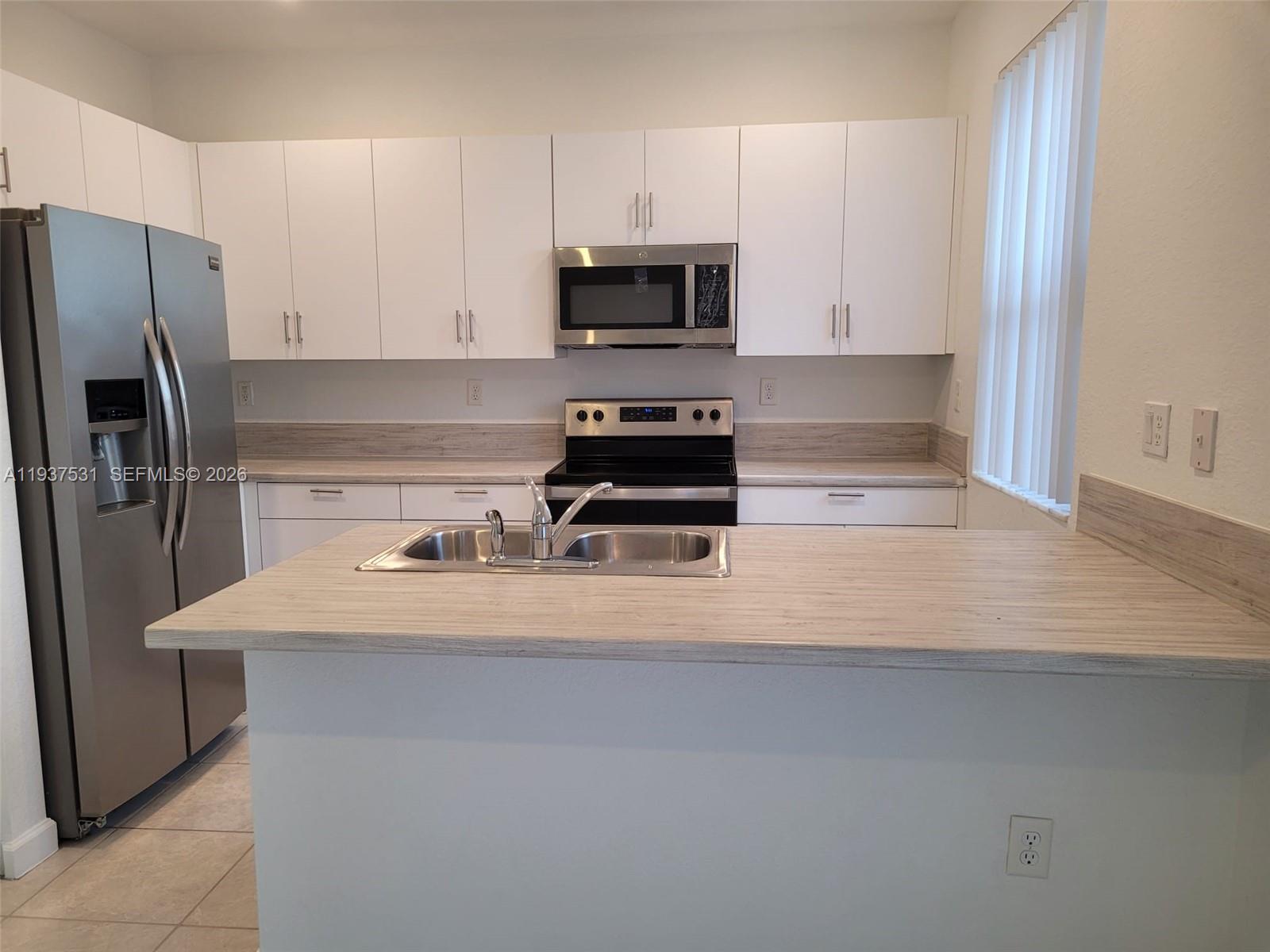 2685 Southeast 13th Street Homestead, FL 33035 - Photo 5 of 18 a kitchen with a sink a microwave and refrigerator
