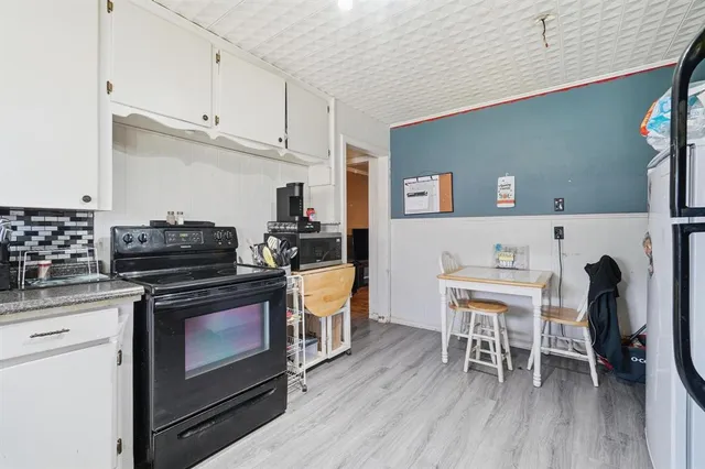a kitchen with a stove and white cabinets with wooden floor