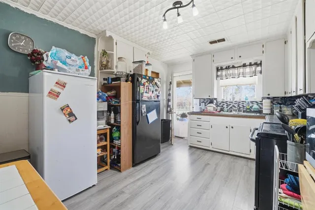 a kitchen with a refrigerator a stove top oven a counter space and wooden floor